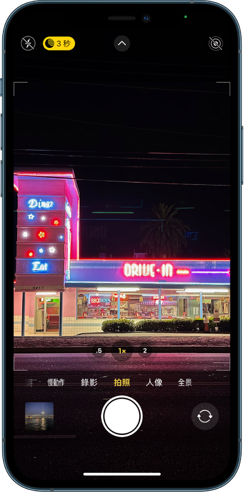 「拍照」模式的「相機」螢幕。閃光燈和「夜間模式」按鈕會顯示在螢幕的左上角。閃光燈已關閉，而「夜間模式」已開啟。「相機控制項目」按鈕位於最上方中央，「原況照片」按鈕位於右上角。螢幕底部由左至右為「照片和影片檢視器」按鈕、「拍照」按鈕和「相機選擇器後置」按鈕。