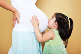 Girl kissing pregnant mother.