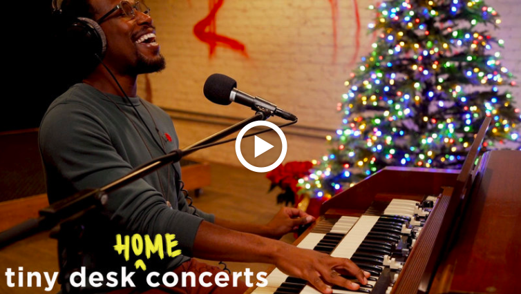 Cory Henry plays the piano with a Christmas tree in the background