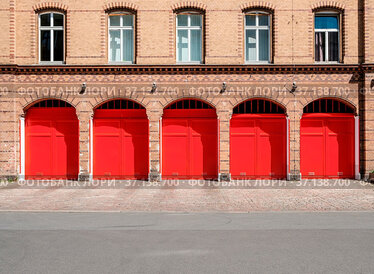 Fire department builidng facade with red doors and empty street