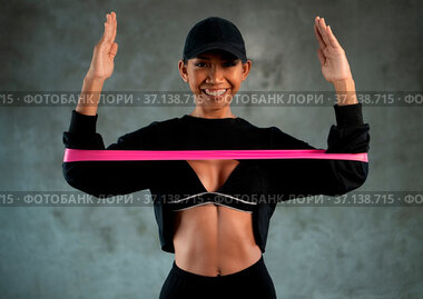 Happy healthy smiling woman working out with resistance band at the...