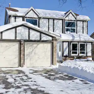 house with snow and ice on driveway