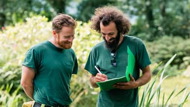 Two landscapers planning a layout in a garden