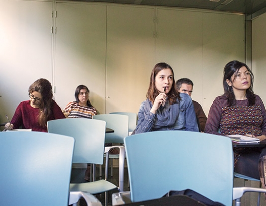 Grup de persones adultes escoltant i prenent apunts en una classe