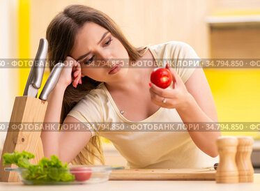 Young woman preparing salad at home in kitchen