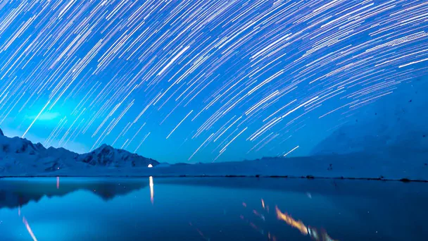 mountains in the distance with lights circling in a night sky