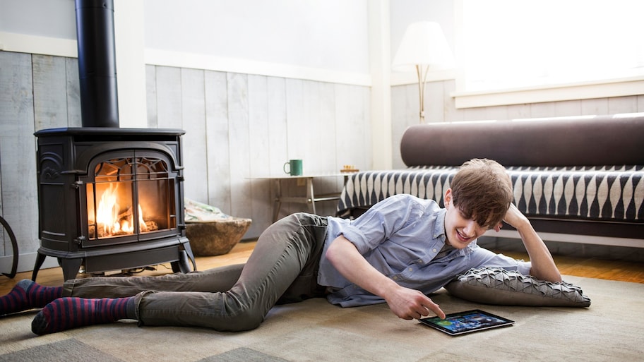 Man lays in front of cozy fire in wood-burning stove