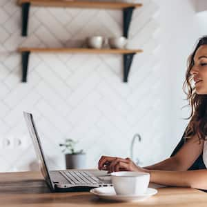 Woman home desk laptop mug plant