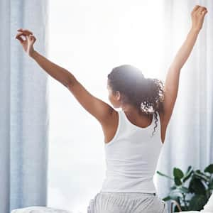 Woman stretching while sitting on her bed in the morning