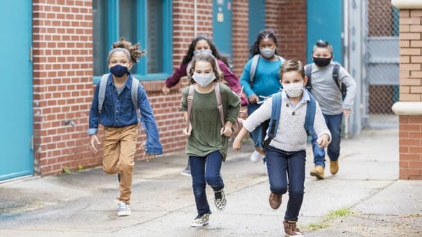 Children wearing masks and backpacks