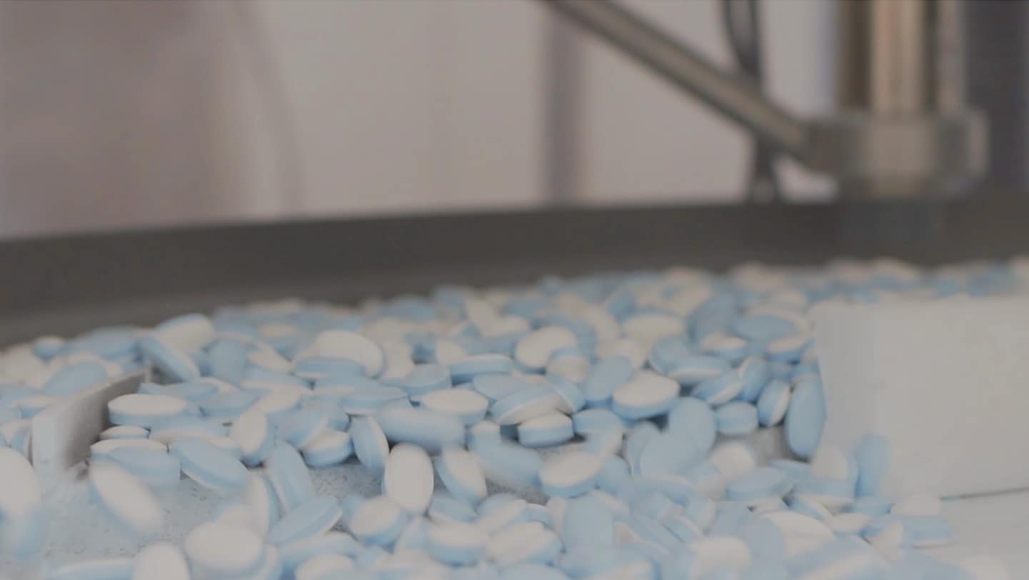 Blue and white pills on a conveyor