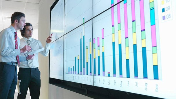 Two business professionals reviewing bar charts on a light wall