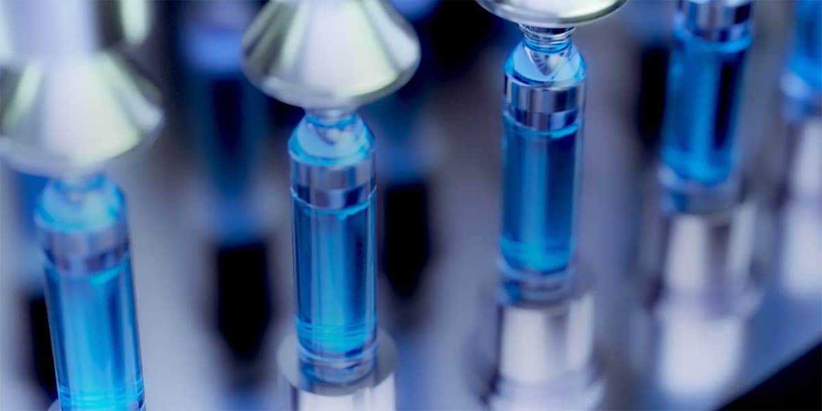 Medical vials being mechanically filled with blue liquid