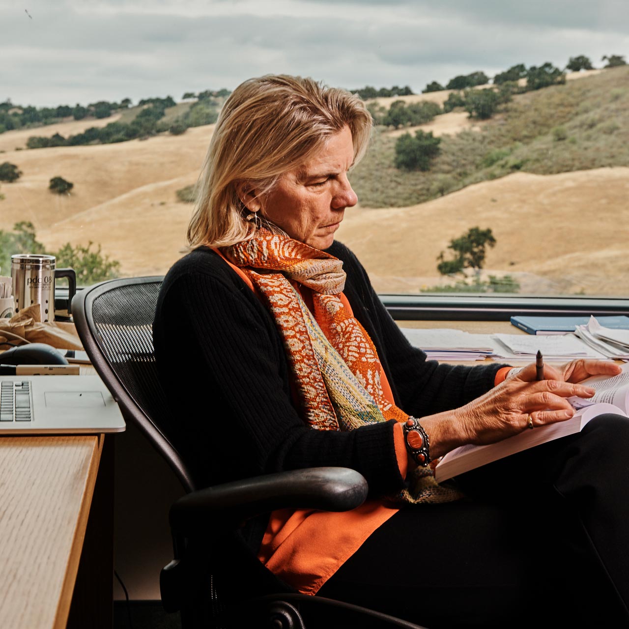 businesswoman sitting at desk reading book on her lap