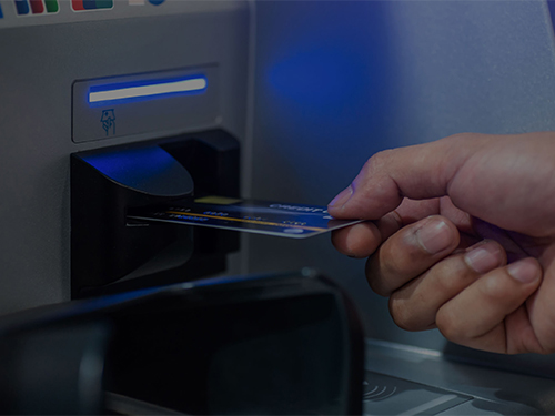 Person putting their ATM card into an ATM machine