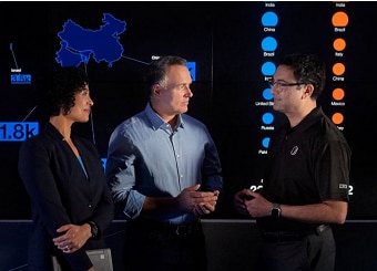 3 people talking in front of a black board with charts displaying far east Asia