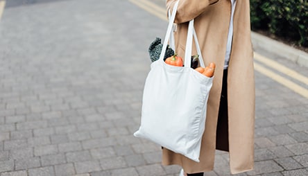 A woman carrying groceries in a reusable bag