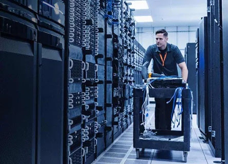 man walking through a server room with a table full of cables