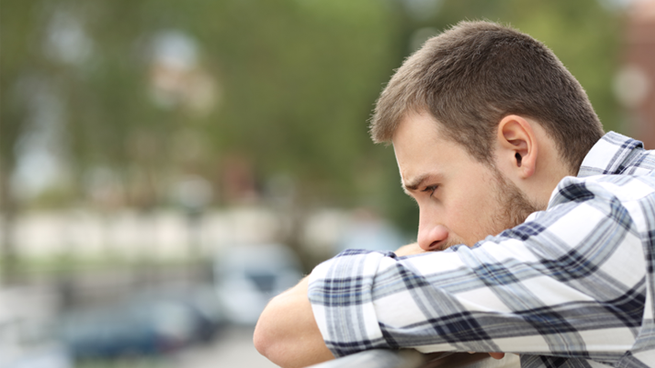 Image of a distressed young man looking off a balcony