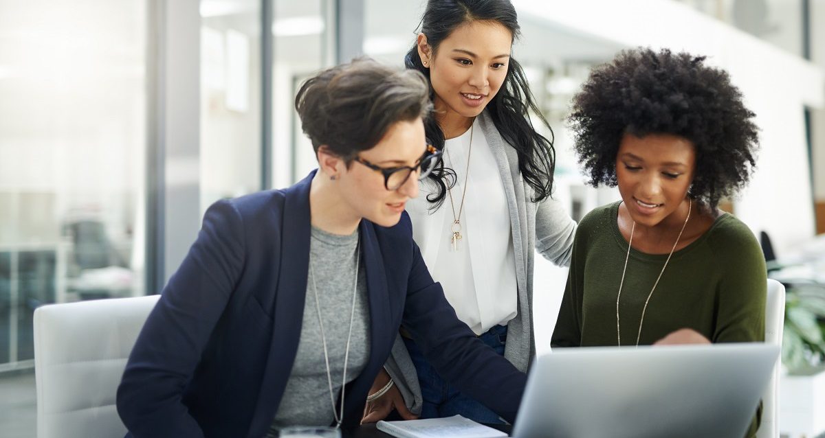 Three businesswomen using a laptop during a meeting at work