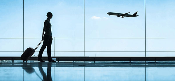 Traveler pulling a suitcase. Airplane in the background.