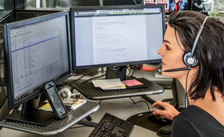 Business woman in front a computer with two monitors engaging on a call.