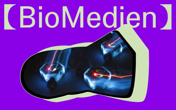 Die Grafik mit lila Hintergrund zeigt als Ausschnitt leuchtende kleine Roboterkreisel bewegen sich auf dunklem Untergrund. Darüber steht in blassem grün der Titel "BioMedia".