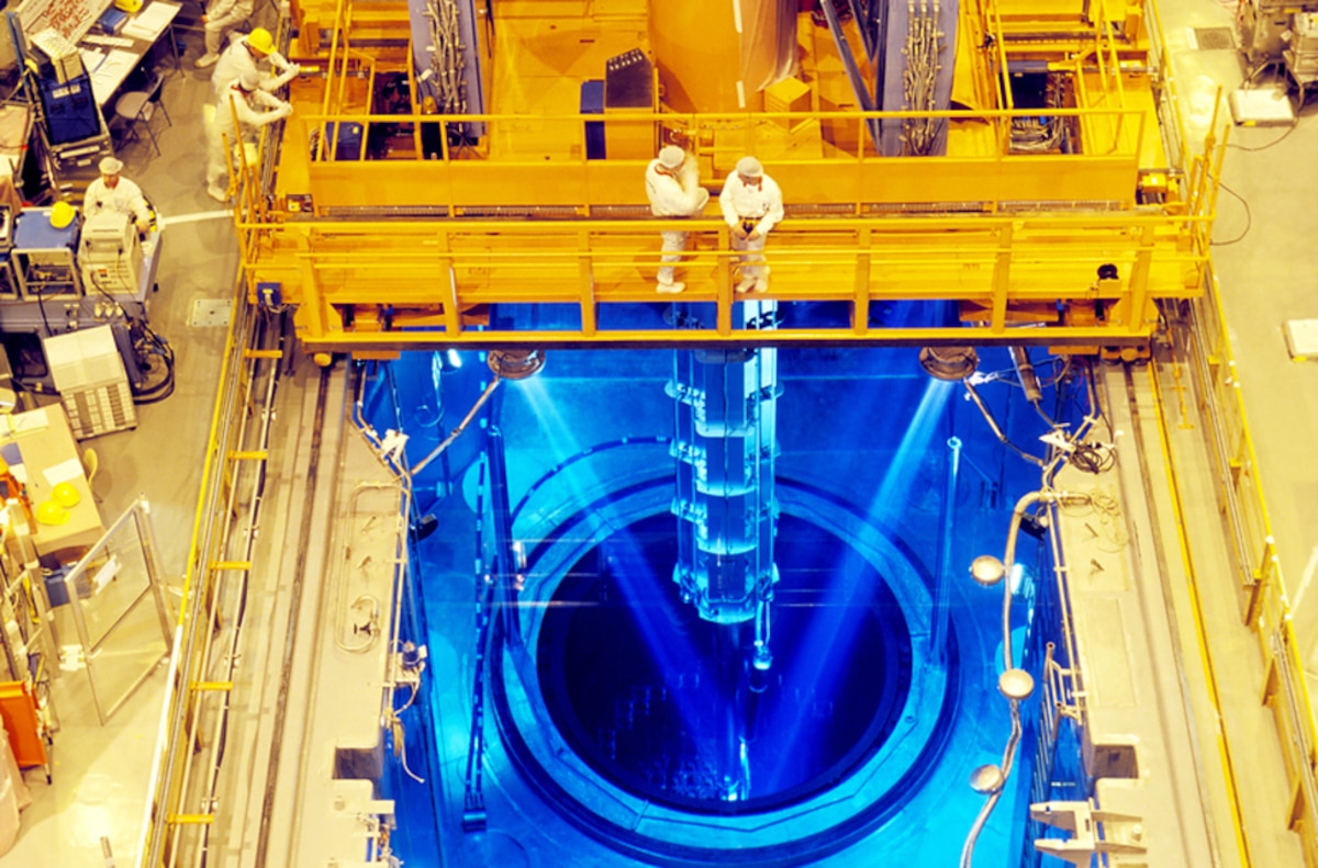 Fuel rods being loaded into a nuclear power station&#039;s reactor core. The reactor itself is immersed beneath the water (blue), and lifting machinery is being used to raise and lower the fuel rods (centre) into the core (circular area).