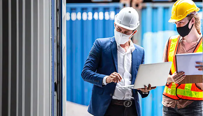 Two people using tablet computers and wearing hard hats