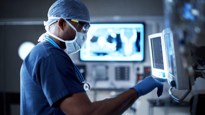 Photo of surgeon standing in front of a computer monitor in an operating room.