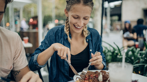 A woman eating a pancake with chocolate, strawberries, and ice cream.