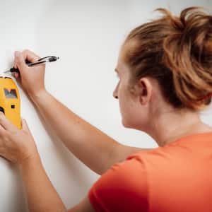 woman using a stud finder on drywall