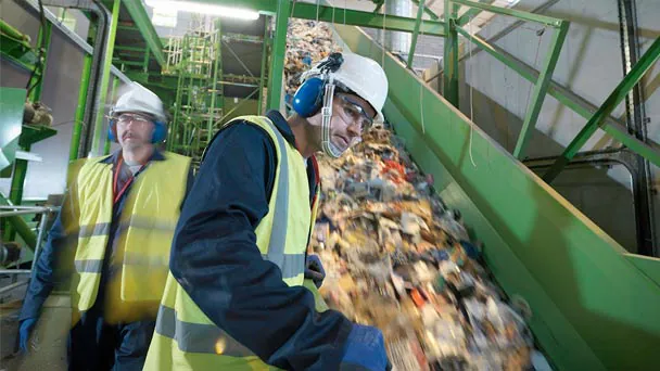 Two people with hardhats working in recycling center
