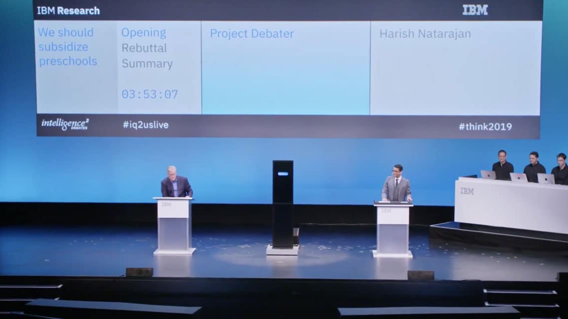 Debaters on stage with an AI construct