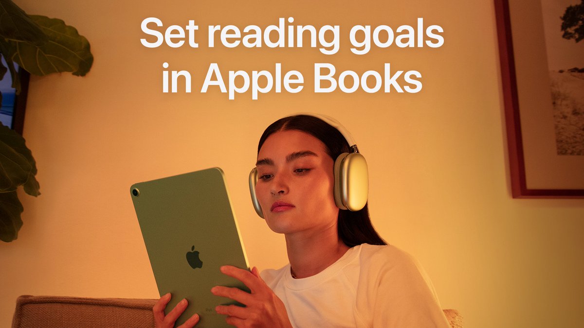 How to set reading goals in Apple Books. Someone is shown reading on their iPad while wearing AirPods Max and sitting on a couch at home.
