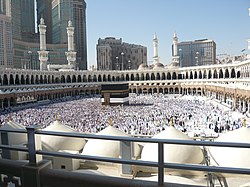 Above: Islam's holiest site, Al-Masjid Al-Ḥarām (The Sacred Mosque), which surrounds the Ka'bah (middle), in Mecca, land of Muhammad's birth and ancestry and an annual point of pilgrimage for millions of Muslims. Below: Map of the Hejaz showing the cities of Mecca, Medina, Jeddah, Yanbu and Tabuk. The Saudi Arabian region is outlined in red and the 1923 Kingdom is in green.