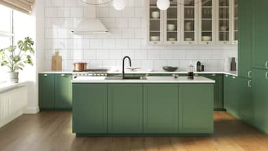 The interior of a kitchen with green cabinets and laminate flooring 