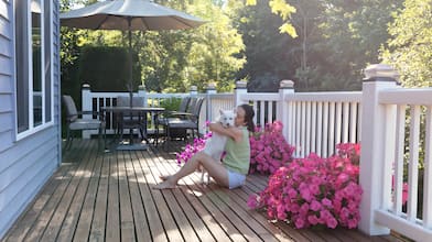 Woman sitting on a wood deck hugging her dog