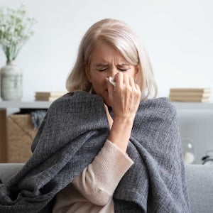 Woman sneezing holding napkin blow out runny nose