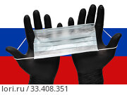 Doctor holds face mask in hands in black medical gloves on background colors flag of Russia or Russian flag. Pandemic insurance coronavirus. Стоковое фото, фотограф А. А. Пирагис / Фотобанк Лори