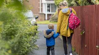 A parent and child walk to school