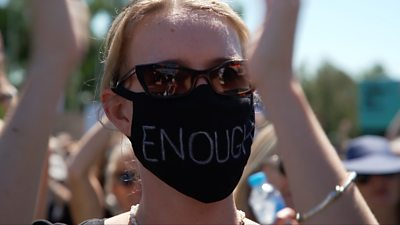 Woman protesting wearing face mask saying enough.