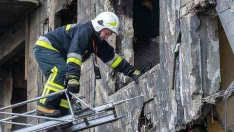 A firefighter climbing a ladder to a badly damaged residential building that was hit by a Russian shell in Kyiv