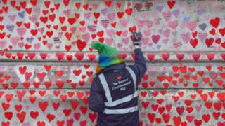 A volunteer paints hearts on the National Covid-19 Memorial Wall in London