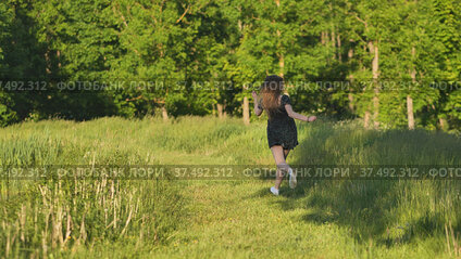 A young girl runs in a meadow on a warm summer evening