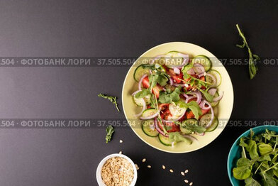 Overhead view of healthy salad in bowl on black background, copy space