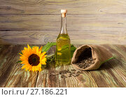 Raw sunflower seeds and organic sunflower oil on a wooden background close-up. Стоковое фото, фотограф Татьяна Ляпи / Фотобанк Лори