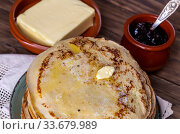 A many of fresh, hot pancakes with butter on a plate and jam in a bowl close-up. Стоковое фото, фотограф Татьяна Ляпи / Фотобанк Лори