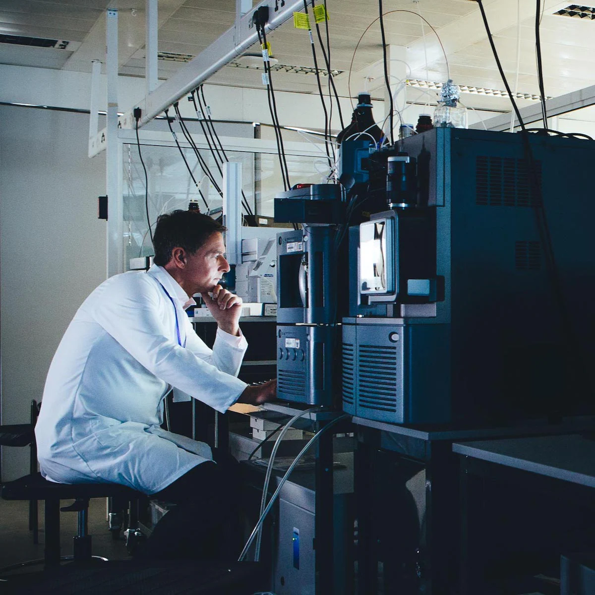 man in lab coat looking at scientific equipment