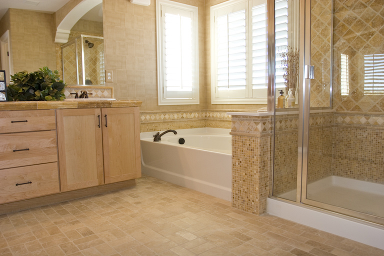 upgraded bathroom with tan tile floor, tub and walk-in shower, and light wood cabinets